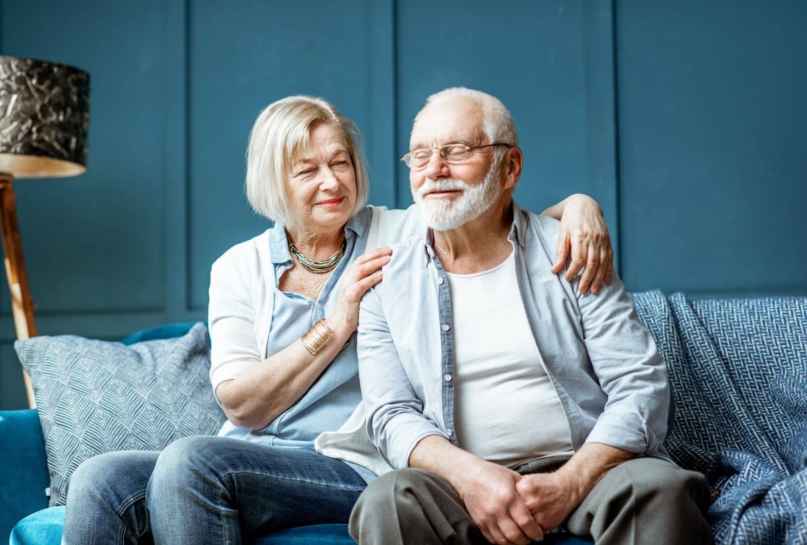 זוג קשישים מחבקים זה את זה בחמימות על ספה בסלון ביתי, מסמל תמיכה משפחתית לניידות נוחה יותר עם תו נכה לרכב.