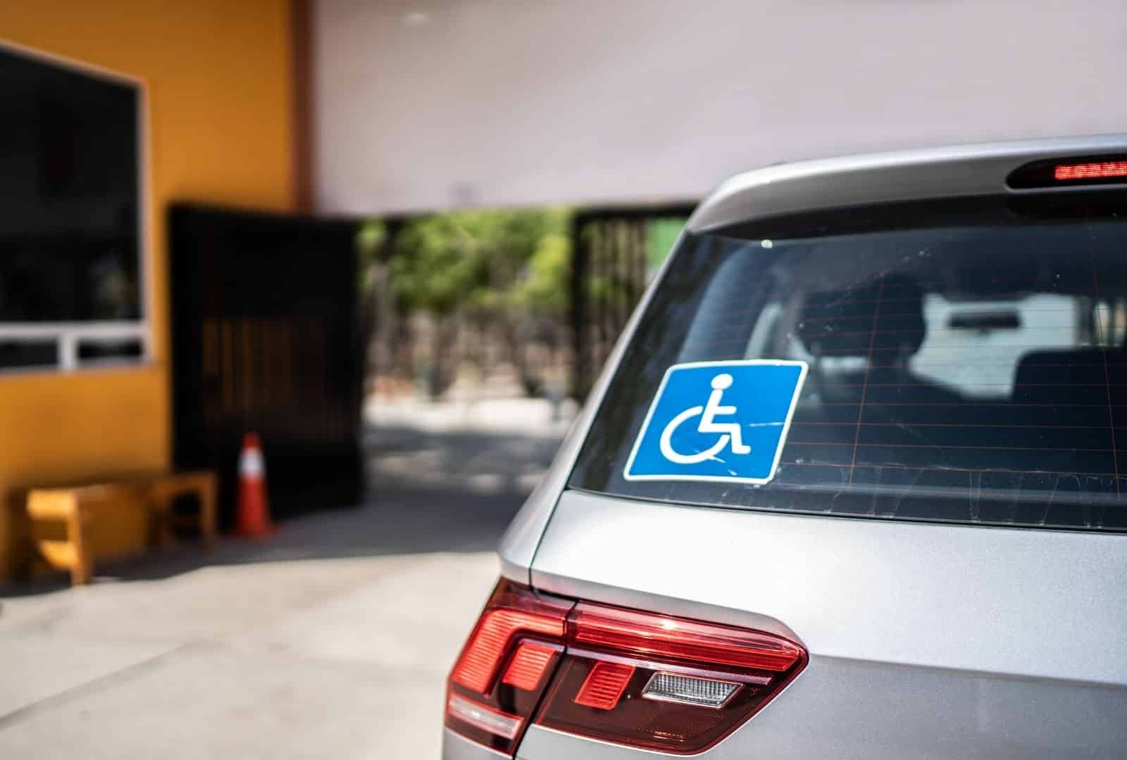 תו נכה כחול על חלון אחורי של רכב לבן בחניה - החלפת תו נכה לרכב